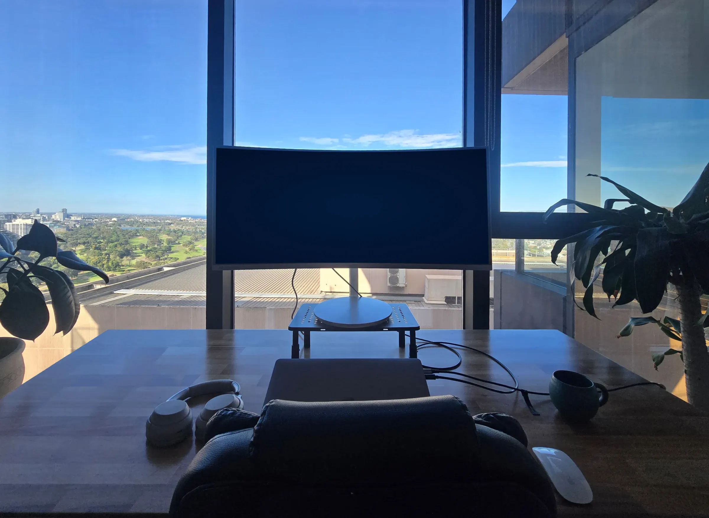 A desk with a curved monitor overlooking the Melbourne skyline
